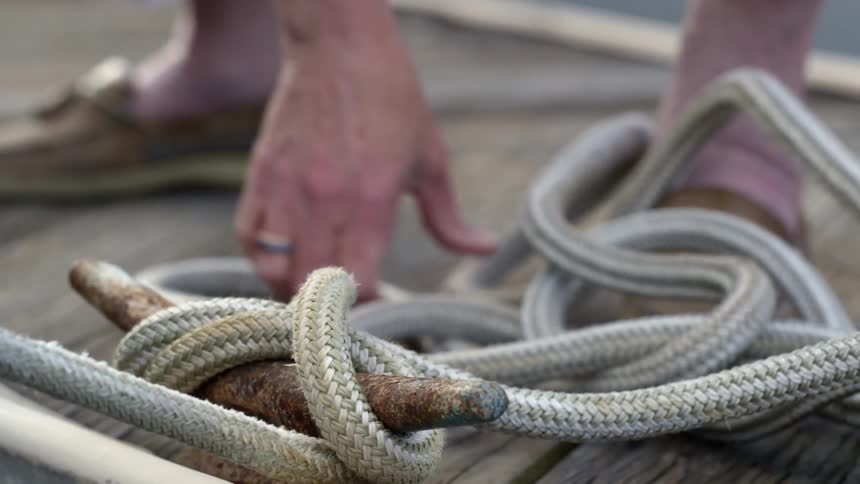 A uses rope to tie their boat to a wooden dock to secure it