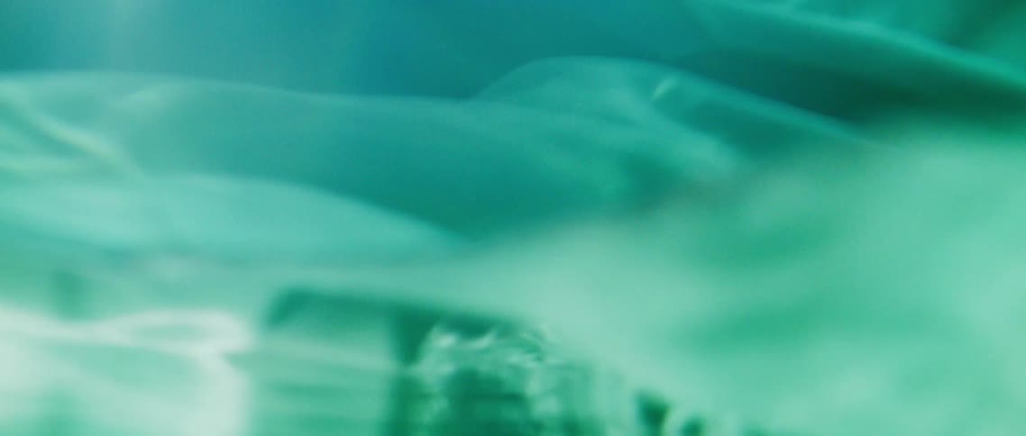Abstract footage of the sun shining down on material floating in water