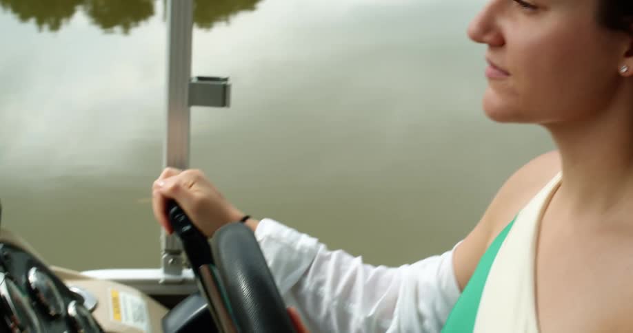 A young woman drives a boat on a lake