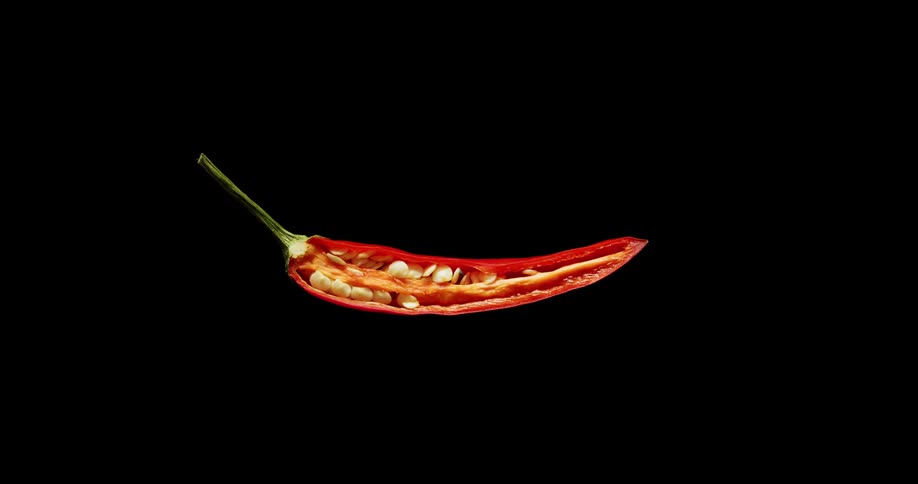A food knife slices a red pepper in half