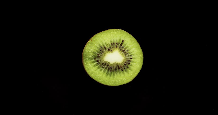 A knife cutting through a kiwi with light and reflection