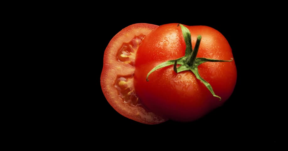 A knife slicing a juicy red tomato in half