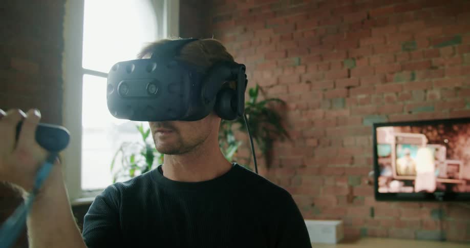 A man plays a virtual reality game with headset and wand