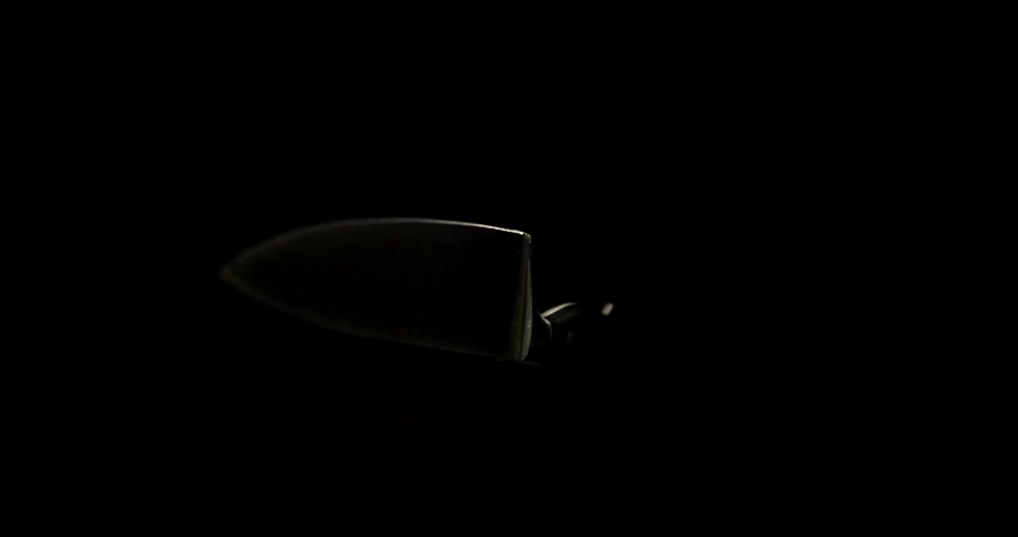 A kitchen knife spins in the air in a dark room