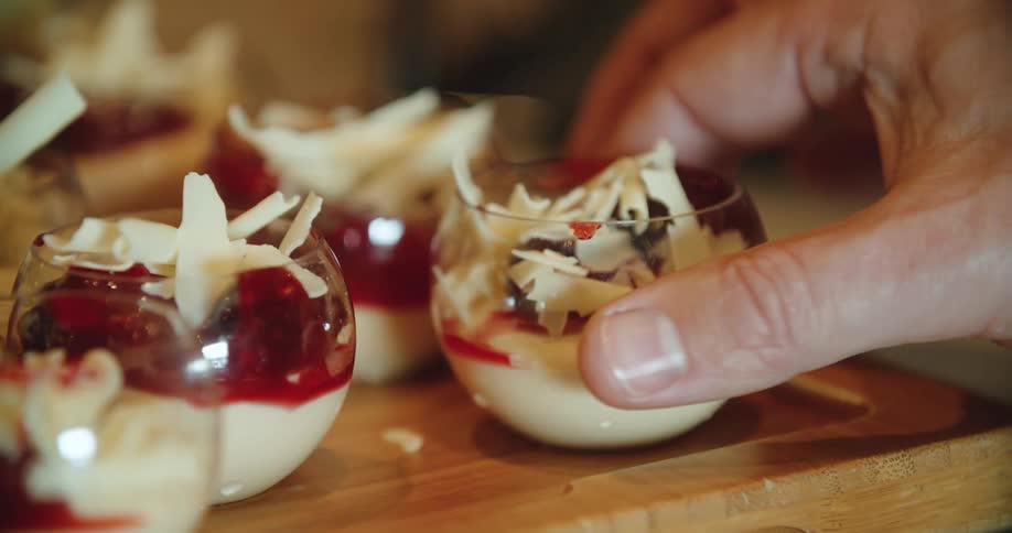 A hand picking up a dessert in a glass bowl