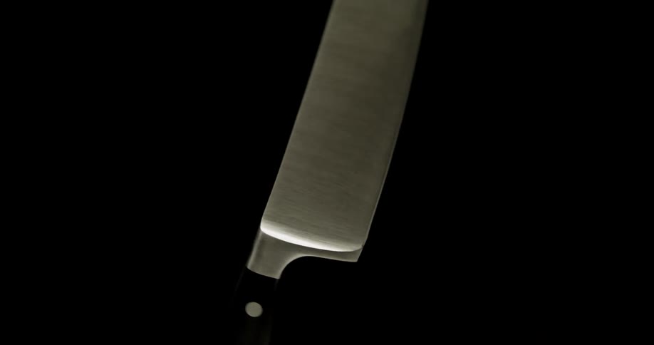 A kitchen knife spins in the air in a dark room