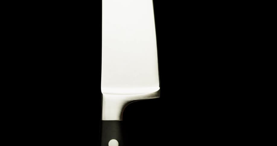 A knife tumbling with light and reflection and a black background