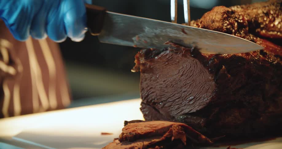 Person slices beef roast on cutting board