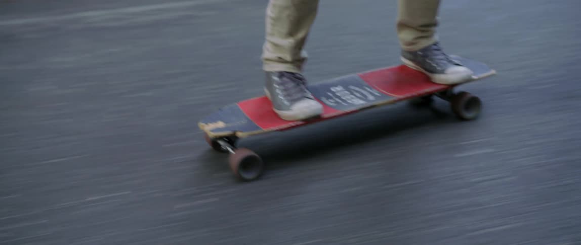 Close up of a man riding a skateboard slowly moving up to his face