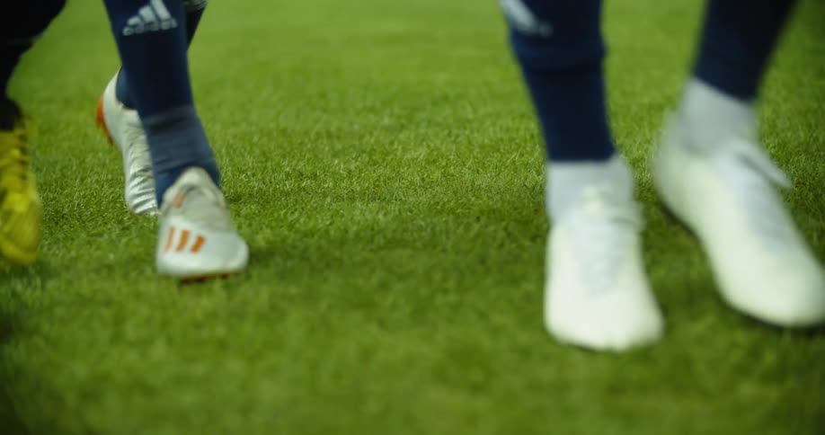 Sports teams wearing cleats walks across field turf
