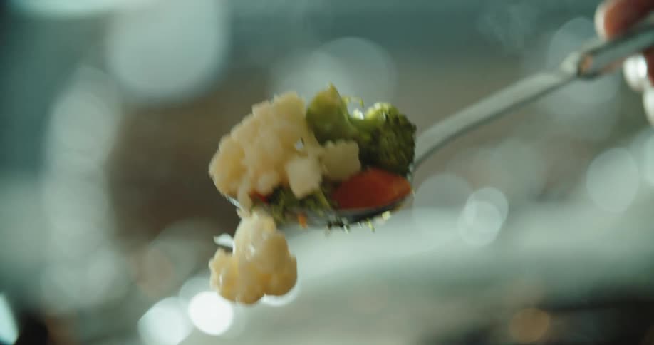 A person dishing up cooked vegetables at dinner