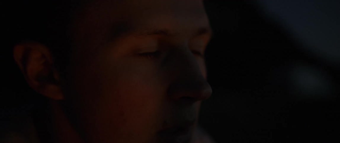 Man sits outside at night with a soft light illuminating his face