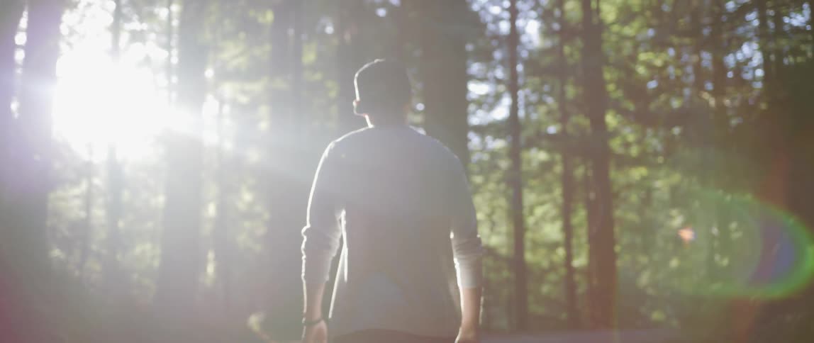 A man is hiking through the forest on a sunny day