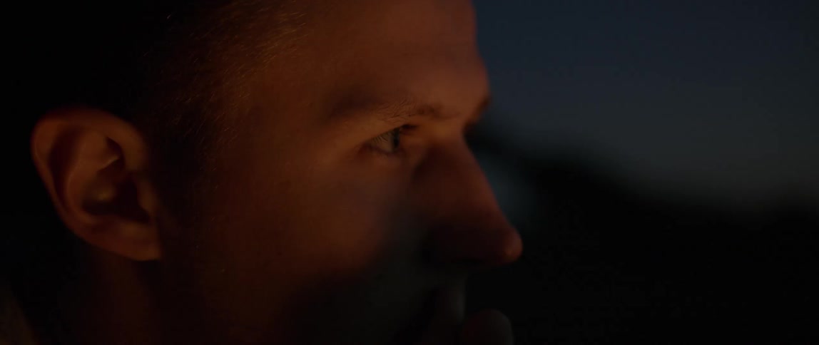 A man's face can be seen with light flashing on it at night