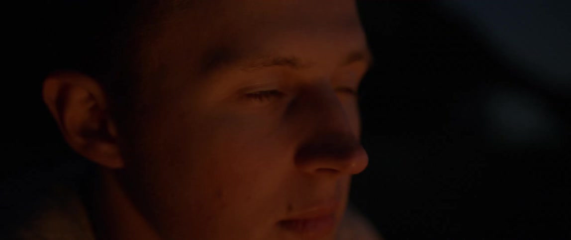 Close up of a persons face as a fire flickers light on it