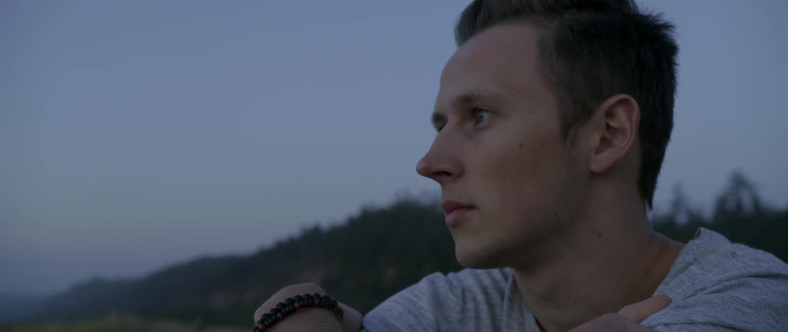 A young man sits outside and looks around
