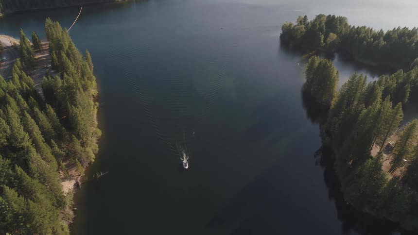 A boat travels across a lake surrounded by evergreen forest