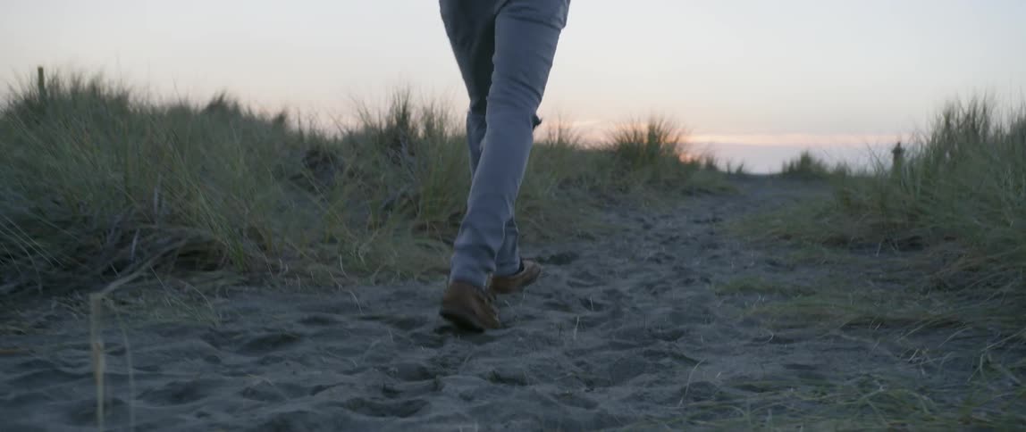 A person walks a sandy trail