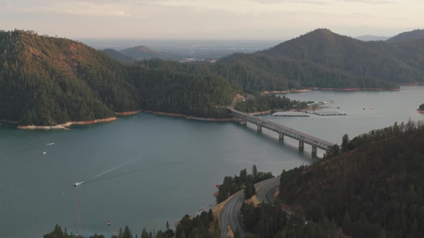 A bridge spans an ocean inlet that is surrounded by dense forests