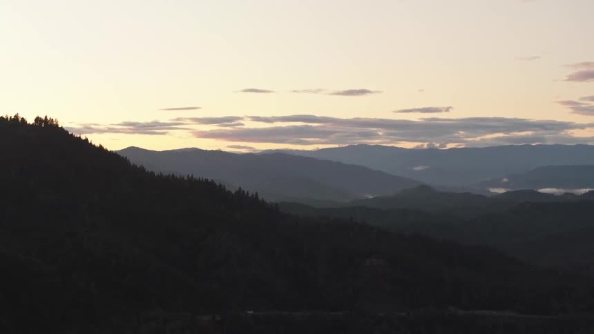 Aerial view of mountain forest being silhouetted against the sky at dusk