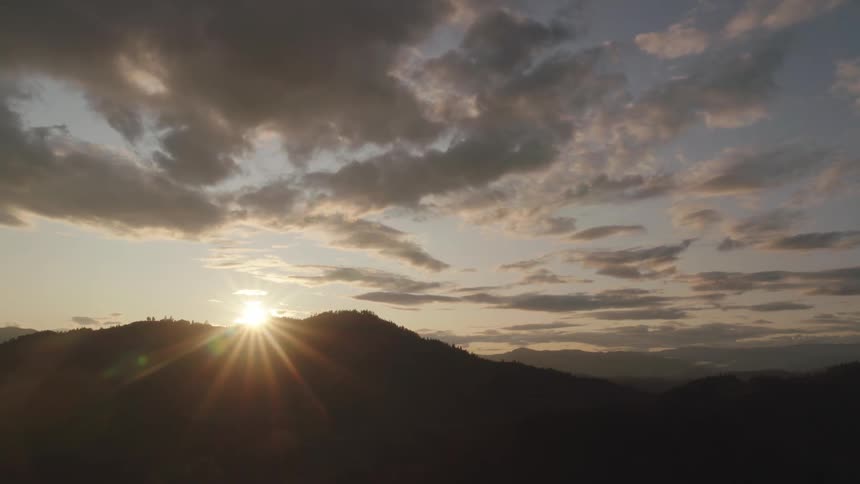 The sun setting over a silhouetted mountain in nature