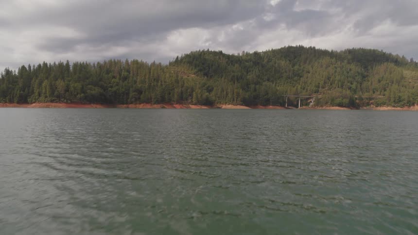 View of a tranquil lake with a mountain forest on a cloudy day