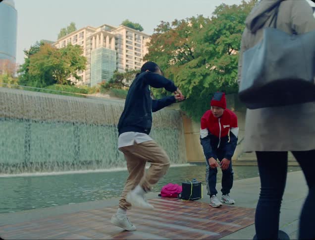 A man high fives a friend as they dance outside a city for money