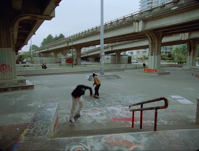 A skateboarder attempts to flip his skateboard while jumping down a staircase but fails and falls to the ground