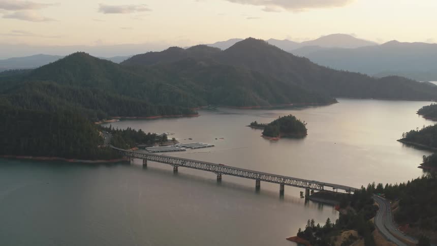 An aerial view of a car traveling over a bridge spanning a lake