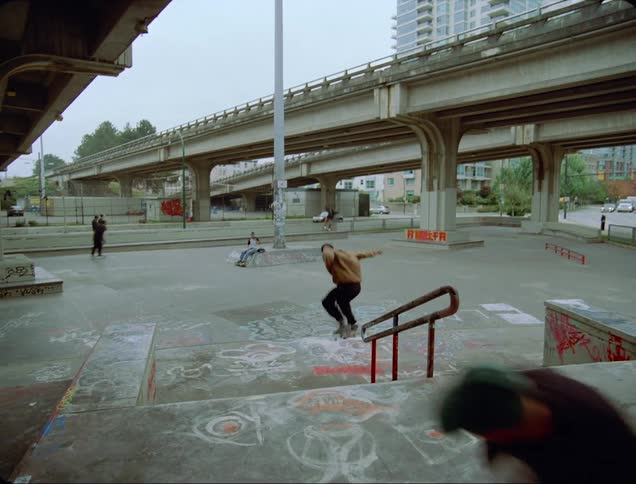 A skateboarder attempts to flip their skateboard while jumping down a staircase but fails and lands on their feet