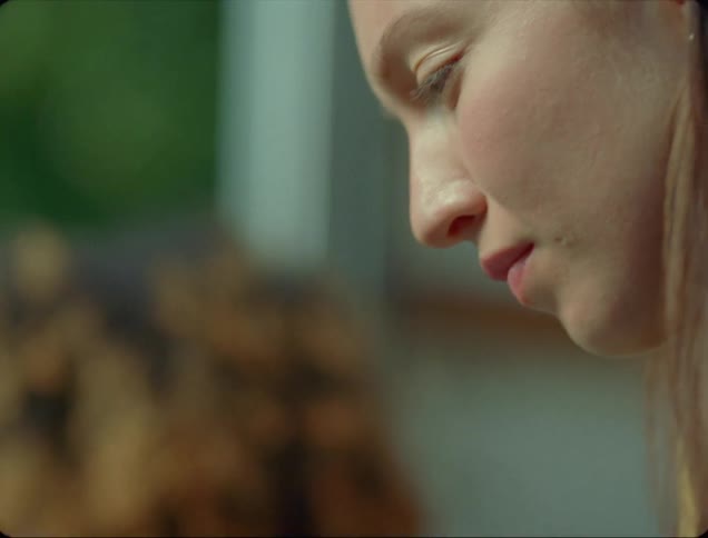 A woman nods while listening to her friend talk as they sit outside