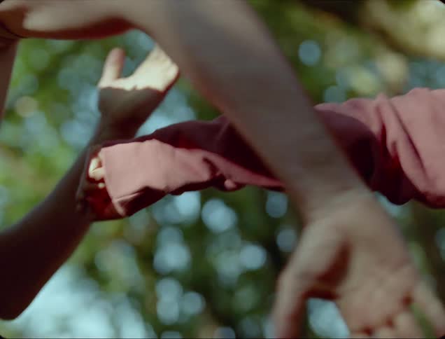 Two people play fighting outside near trees