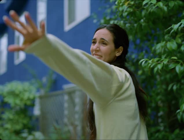 A woman smiles and laughs while talking to a friend before she waves goodbye and walks off with her other friend