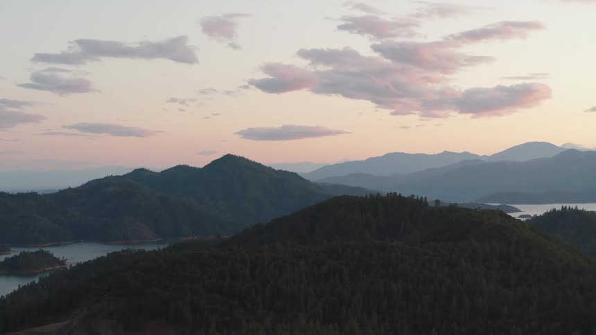 A mountain covered in a forest rises up near a lake