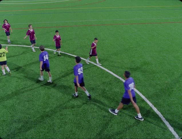 Soccer players walk past each other waving