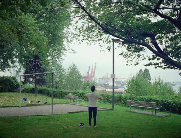 A man stands in a public park by a swing set in meditation
