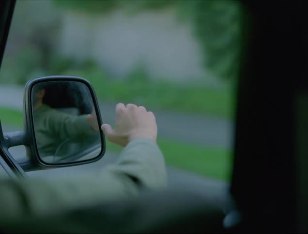 A man hangs his arm out a truck window while driving