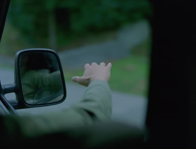 A man riding in the front seat of a vehicle sticks his arm out of the window