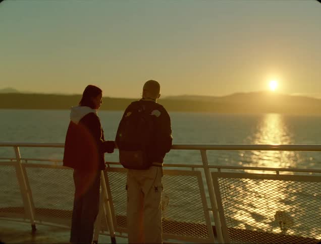 Two people on a dock look out at the water