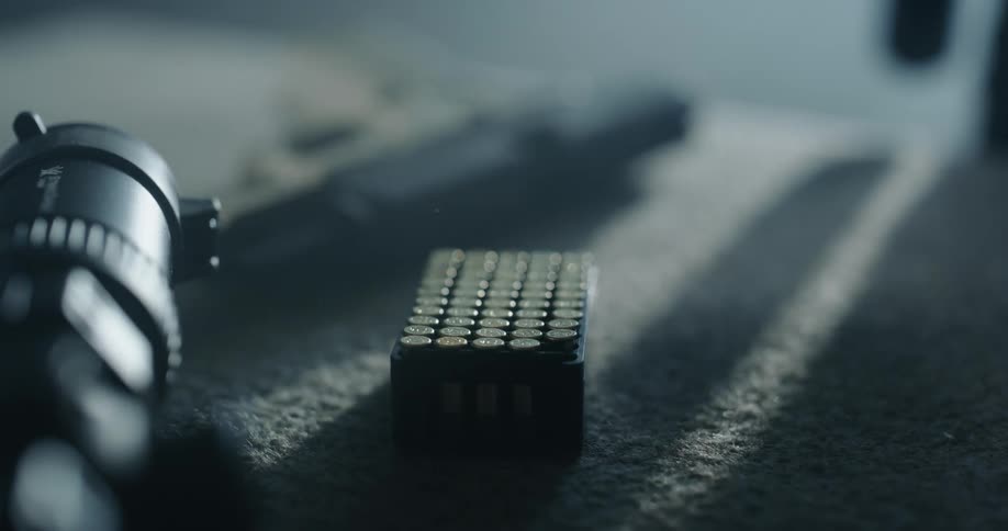 A woman with painted nails retrieves a bullet from a case on a table