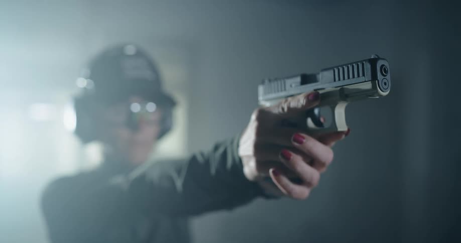 Person wearing eye and ear protection aims handgun