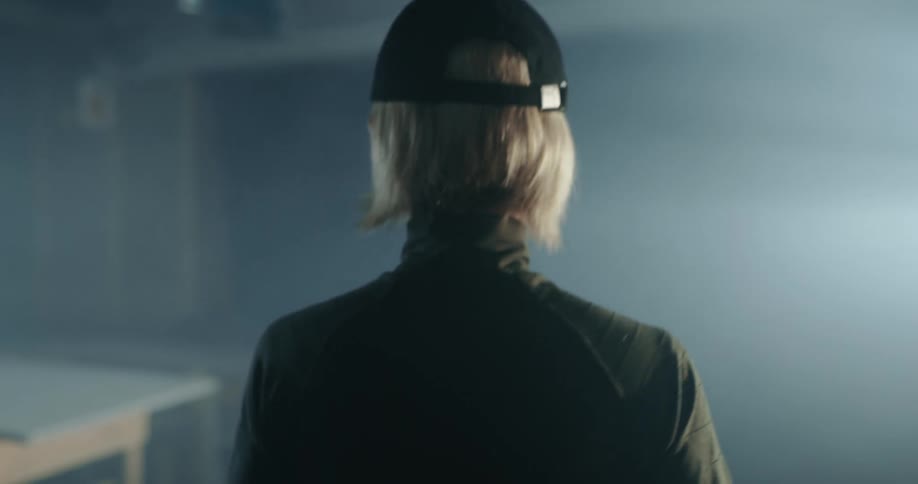 A short haired woman wearing a baseball cap walks through a shooting range