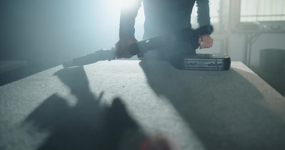 A man places a large rifle on the table