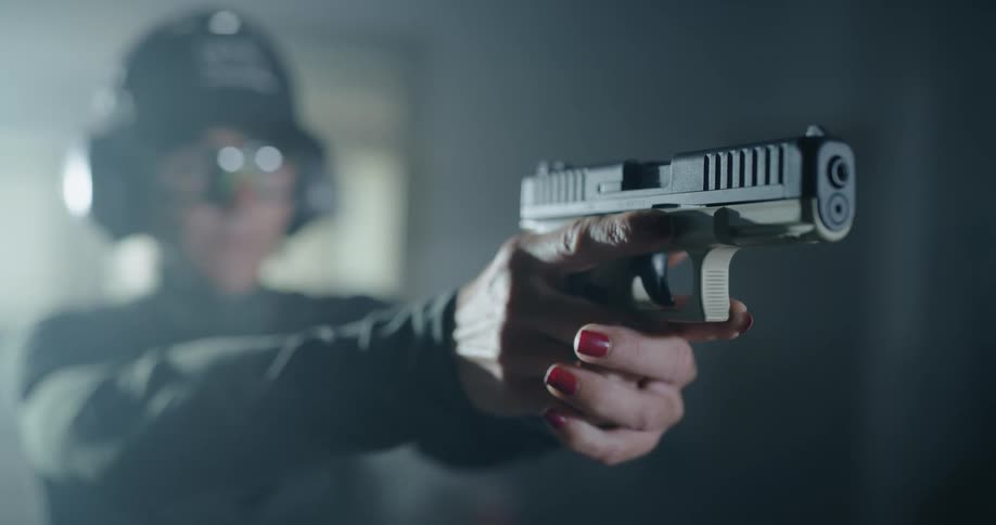 Woman at gun range draws and aims handgun