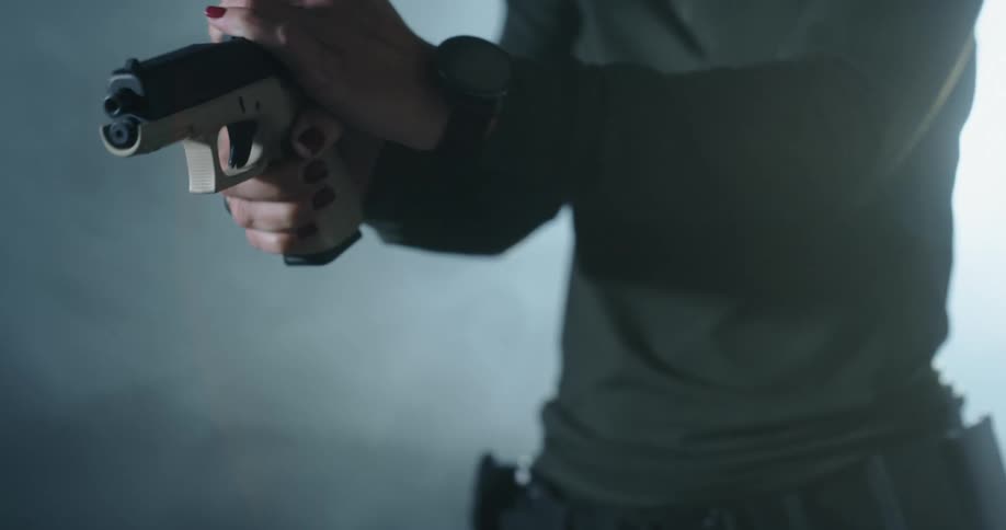 A woman removes a pistol from a gun case and unloads the clip before sitting the pistol on a table