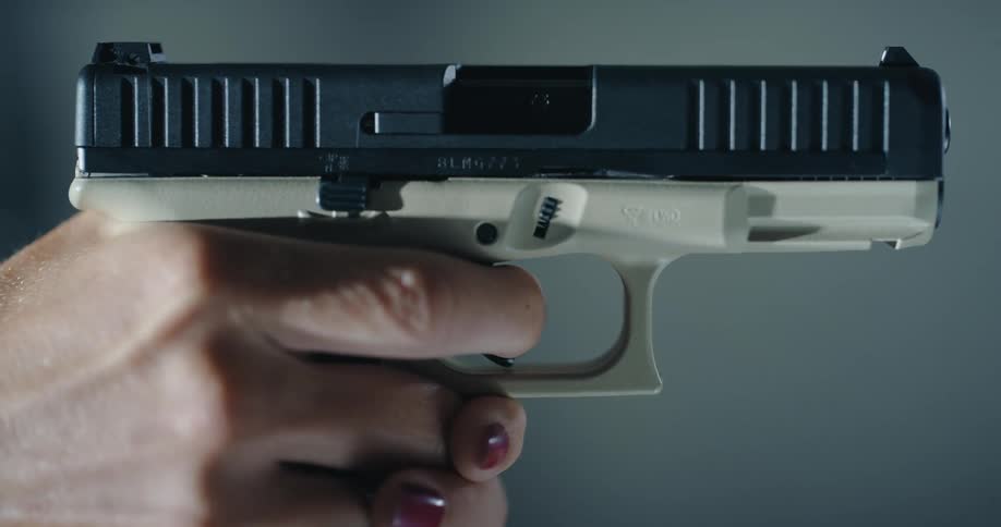 A woman puts her finger on the trigger on a pistol