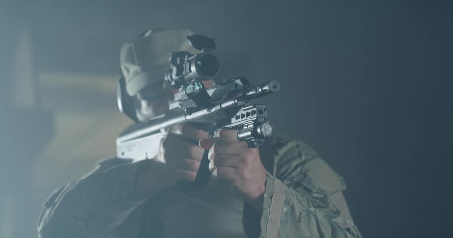 A man in a military uniform shoots a rifle