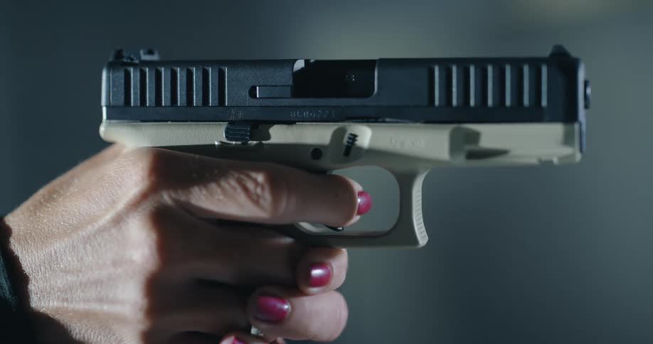 A woman aiming a pistol slowly moves her finger from the trigger guard to the trigger