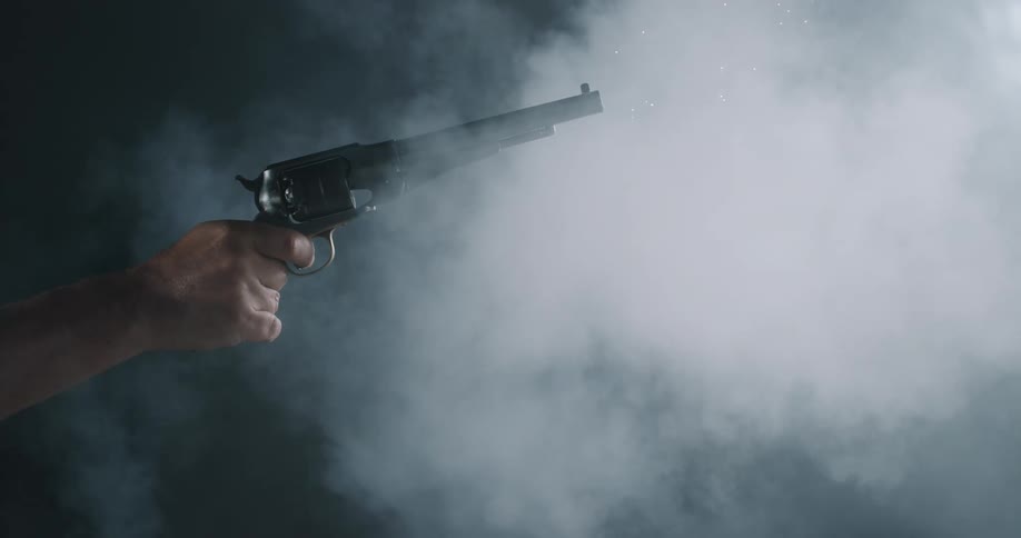 A man fires a long revolver in a smoky room