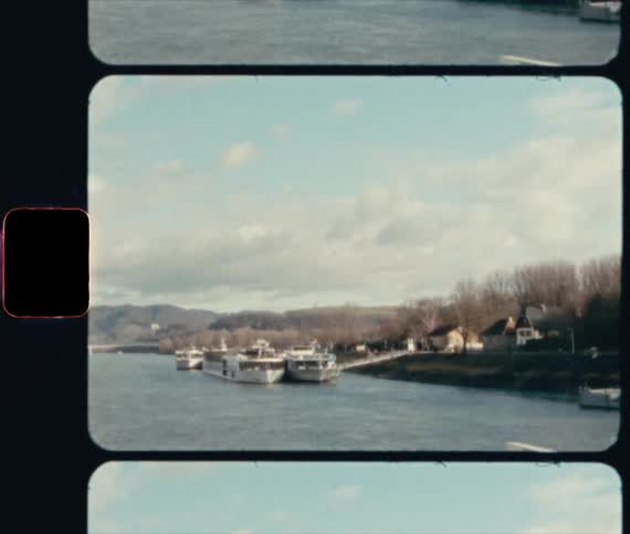 Boats sit at dock near houses and leafless trees with low mountains on the horizon